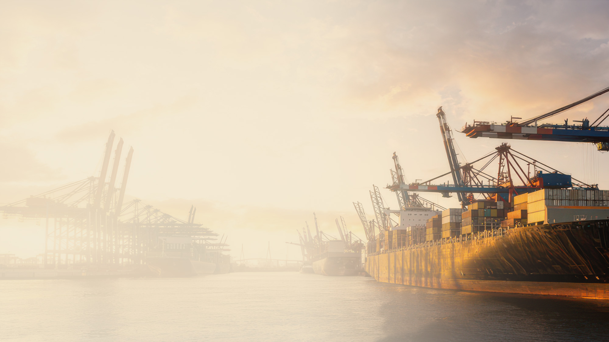 Containerhamn med stora lastkranar och fartyg i kvällsljus